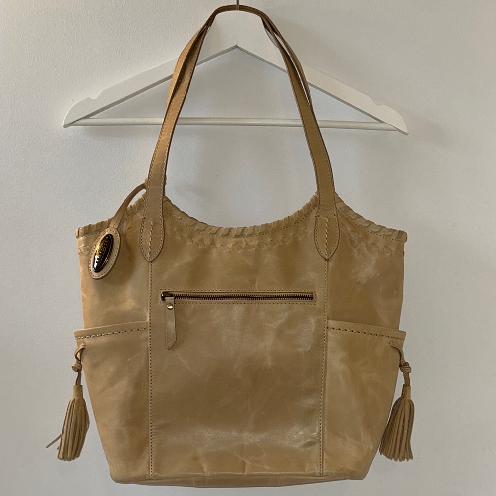 Born tan leather shoulder bag with leather threading and tassles detail.